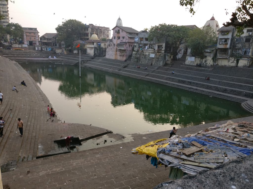 A large rectangular pool of green water surrounded by buildings.