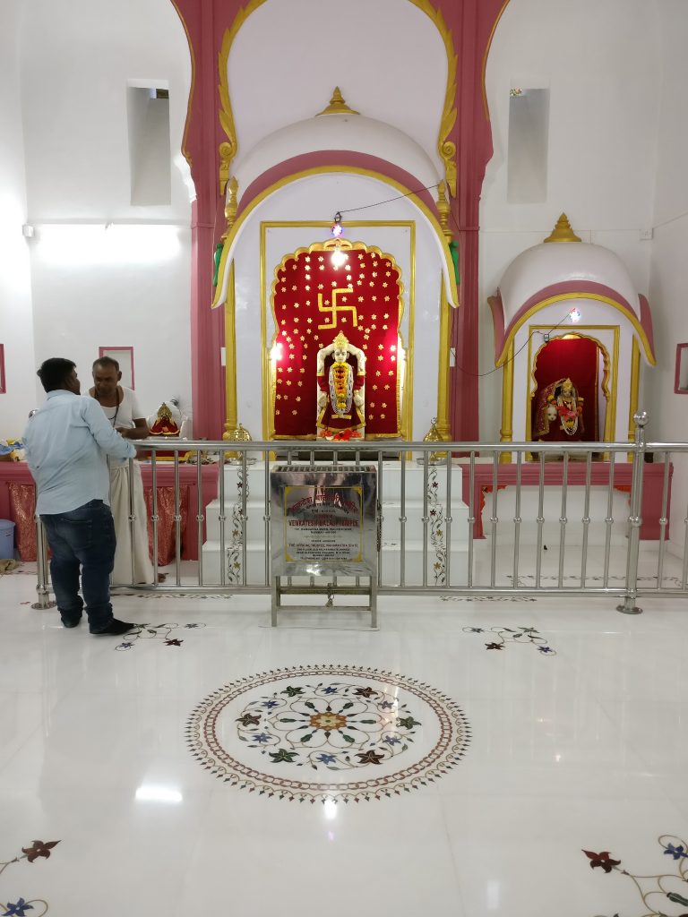 A bright white room with a red altar at the far end, with a low fence around it.