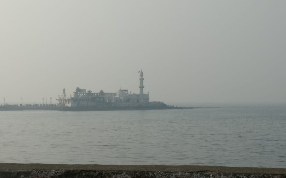 The mosque seen across an expanse of water, rather fuzzy because of the smog.