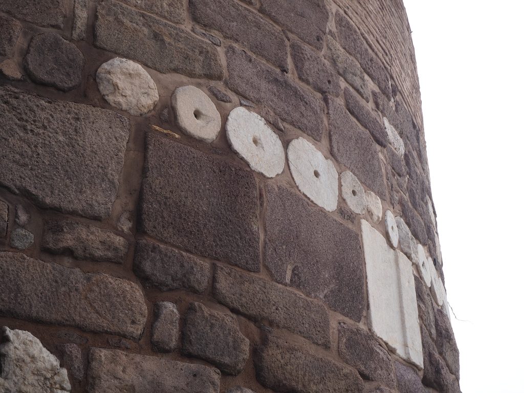 A rounded wall of dark stone, but with round white stones visible.
