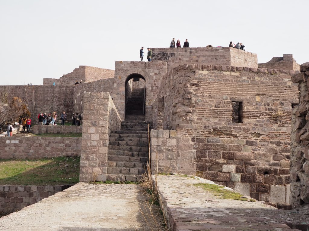 Walls and stairways and archways in a cluster, with people standing on top of some of the walls.