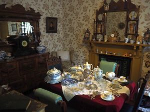 A dining room in Wick Heritage Museum. Notice the sheer quantity of dishes and other objects on the tabel and mantel.