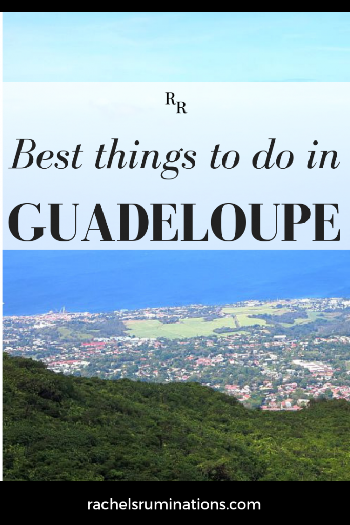 Pinnable image
text: best things to do in Guadeloupe
image: view from a mountain over a village with the blue sea in the distance