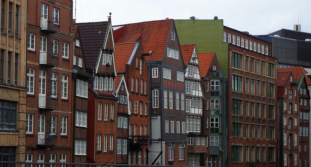 The builidings are tall and narrow with lots of windows, mostly red-brick. Some have half-timbered elements.