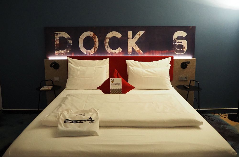 Looking from the foot of the bed, a double bed with red headboard and, above that, the words DOCK 6.