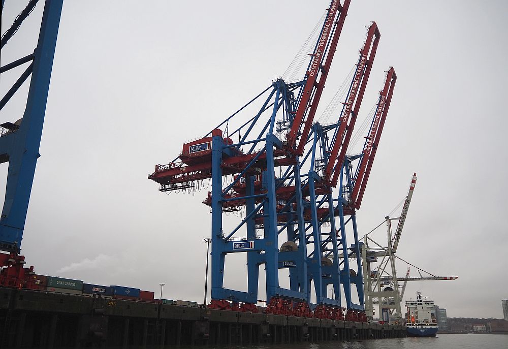 a row of blue and red cranes line a dock in Hamburg