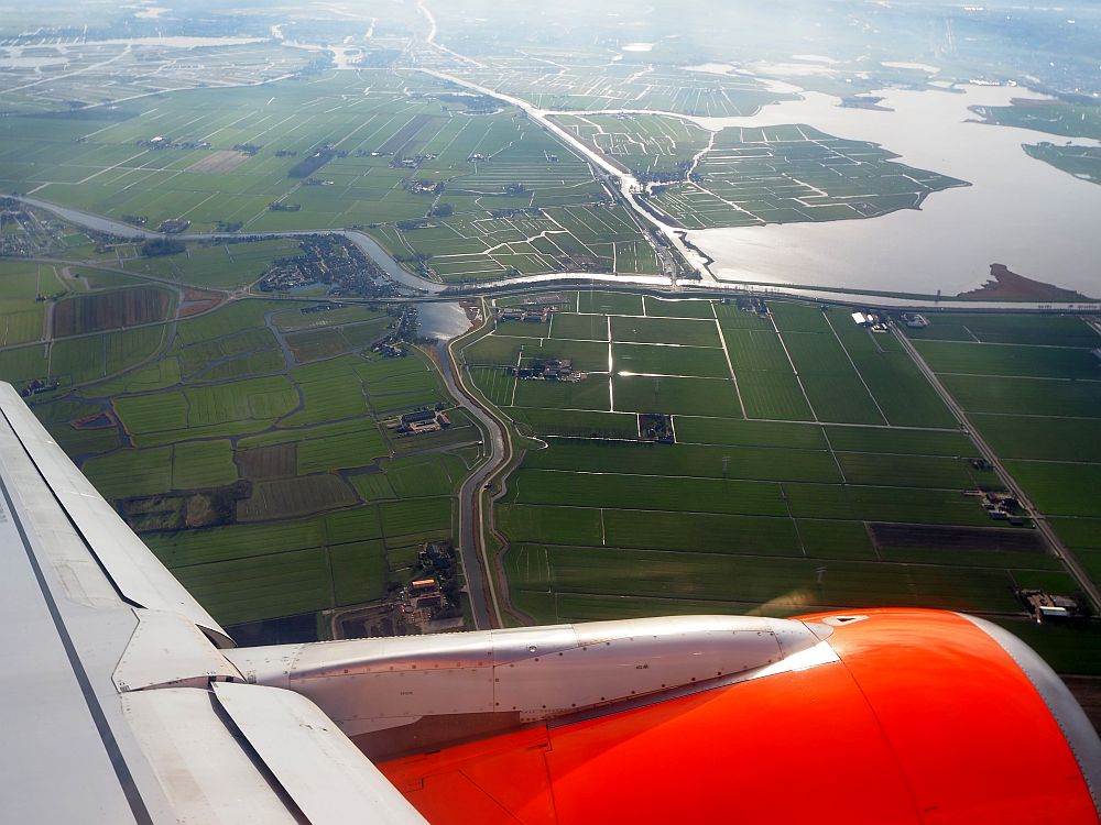 the view out of an easyJet flight shows a bit of the left engine and wing and, below, green fields edged by ditches.