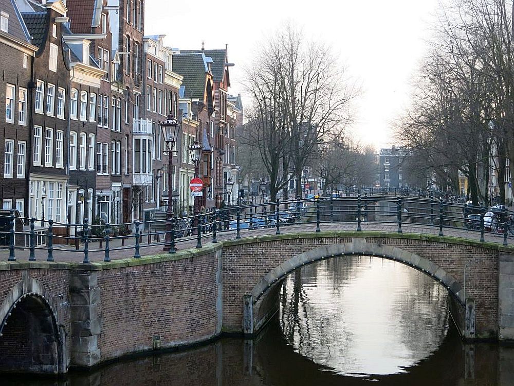 A typical scene in old Amsterdam: a canal, a small bridge over it, and Golden Age brick row houses along the canal.