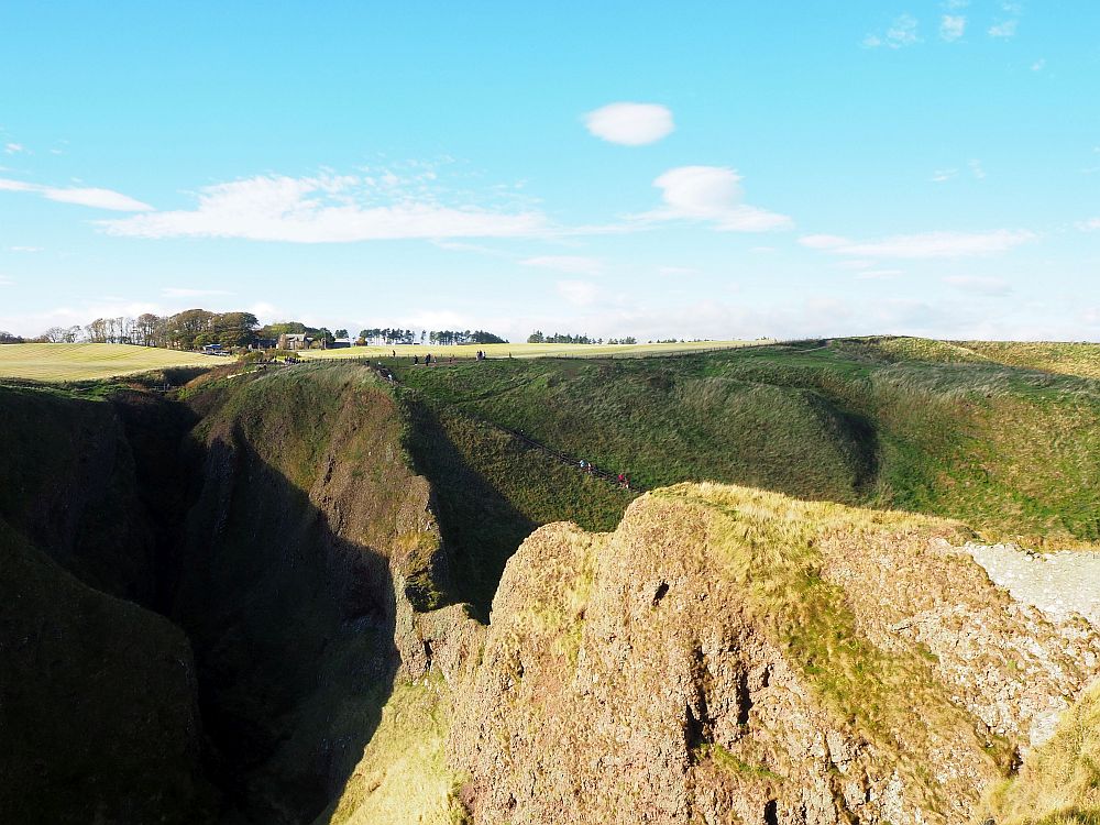  In this view from Dunnottar castle, you can see the ridge of land that connects the castle to the mainland. If you look closely, you can also see the stairway visitors use to get to the castle from the parking lot: down the stairway and then back up to the castle.  