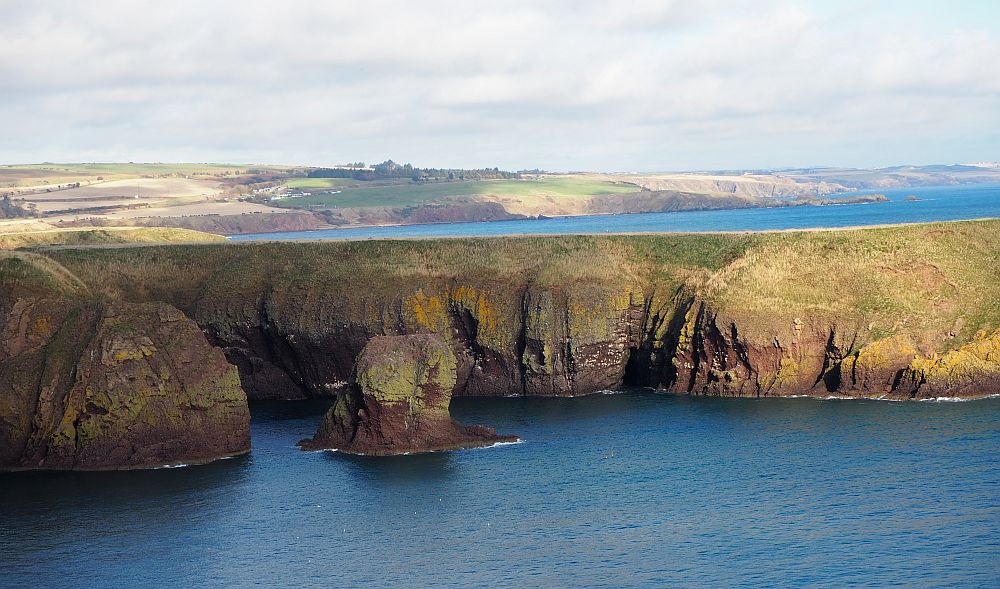 Beautiful views across the water from Dunnottar: flat-topped cliffs and blue water.