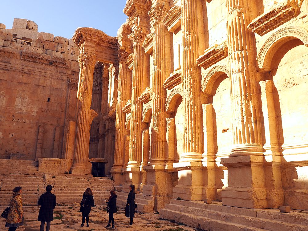 A group of people from my tour group stand at the bottom of the picture, looking up at the walls, which tower above them: I'd guess 4-5 stories high. The walls are carved with half-columns with Corinthian capitals (top pieces). Between the columns are archways, but just decorative; they're not open to the outside of the temple.