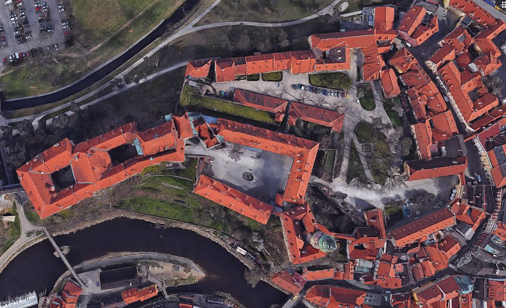 view of the castle from above, which looks just like a collection of buildings with orange roofs.