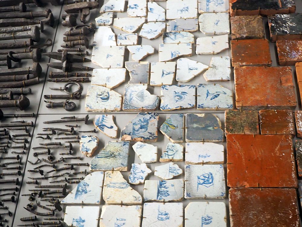 The Delft tiles are white with blue line drawings on each. The floor tiles are clay red.