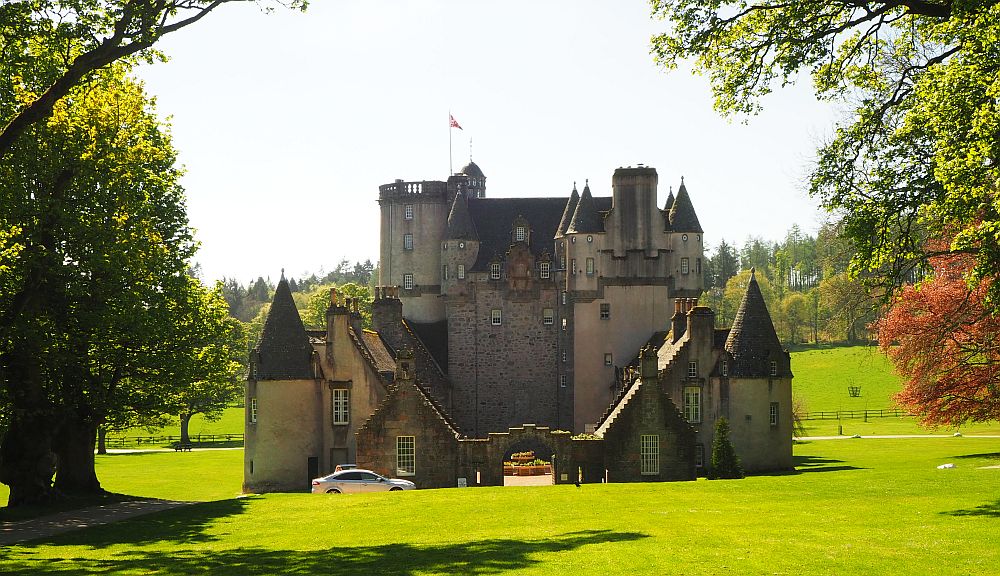 Set on a flat site, Castle Fraser has a tall section at the back of this view and lower wings circling a court in front.