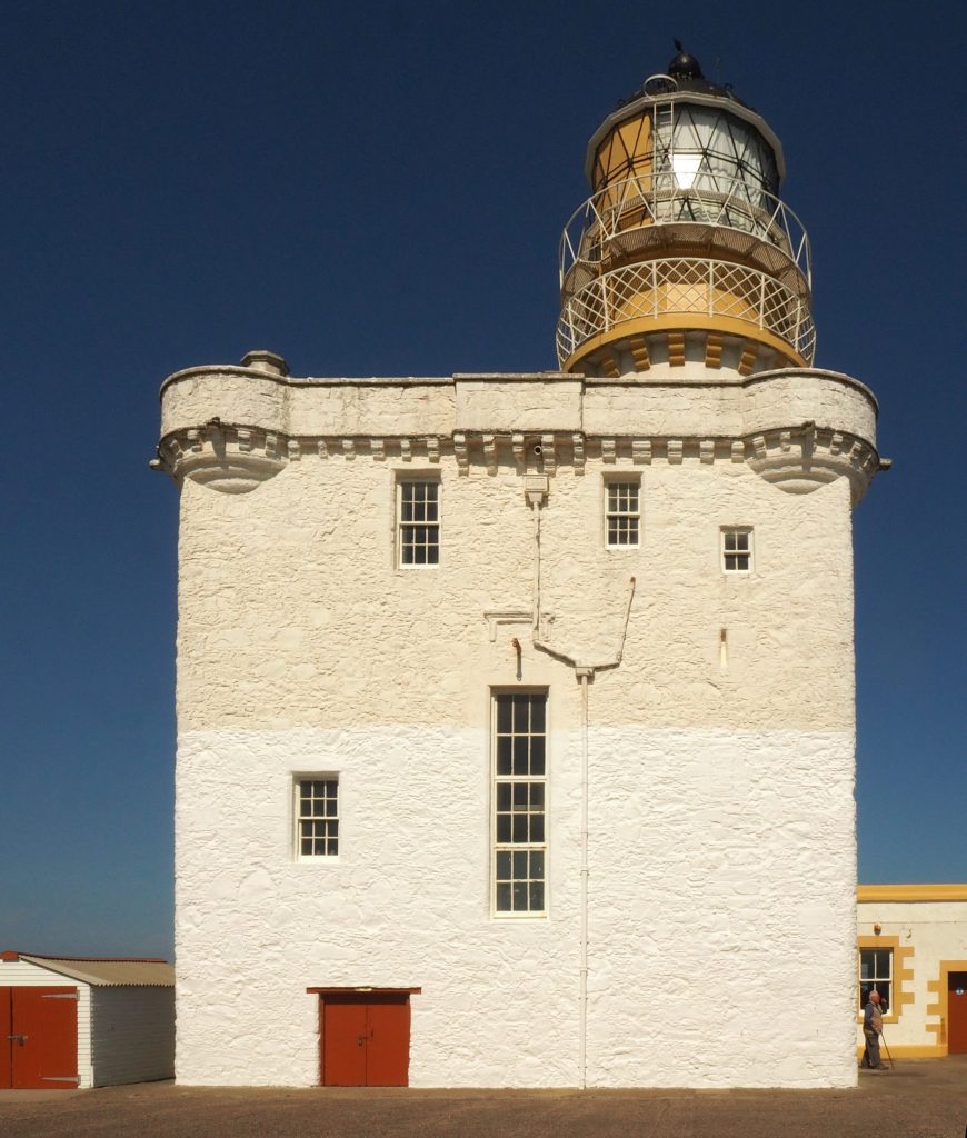 A plain white block of a castle tower, topped with a lighthouse light.