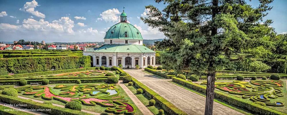 plantings in the foreground are ornately-trimmed in baroque style geometric patterns. In the background, a green-domed, round folly, called the Rotunda.