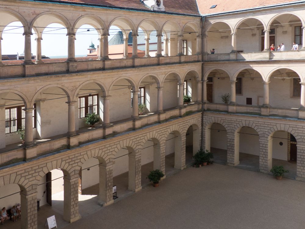 The two sides of the courtyard shown in the photo are made up of columns, holding up arches. There are three rows of the columns and arches piled on top of each other.