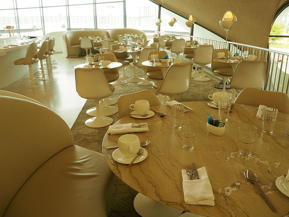 The restaurant is all in whte and light brown, with pedestal bucket chairs.