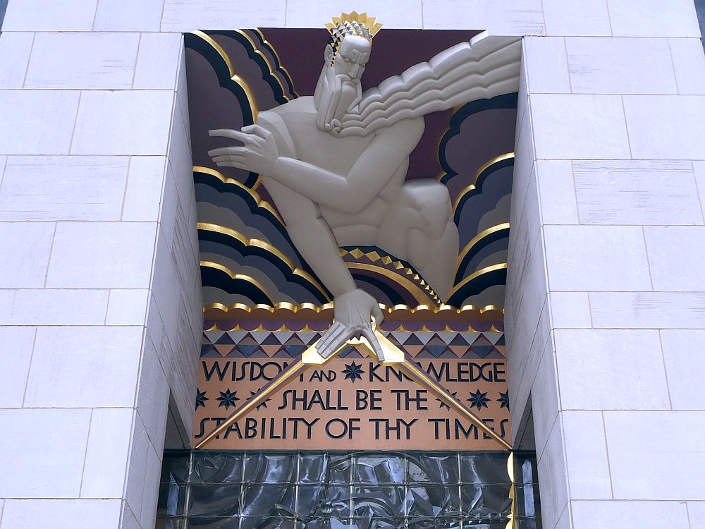 The figure of a god leans over the entrance. Underneath it is the text "Wisdom and knowledge shall be the stability of thy times." 