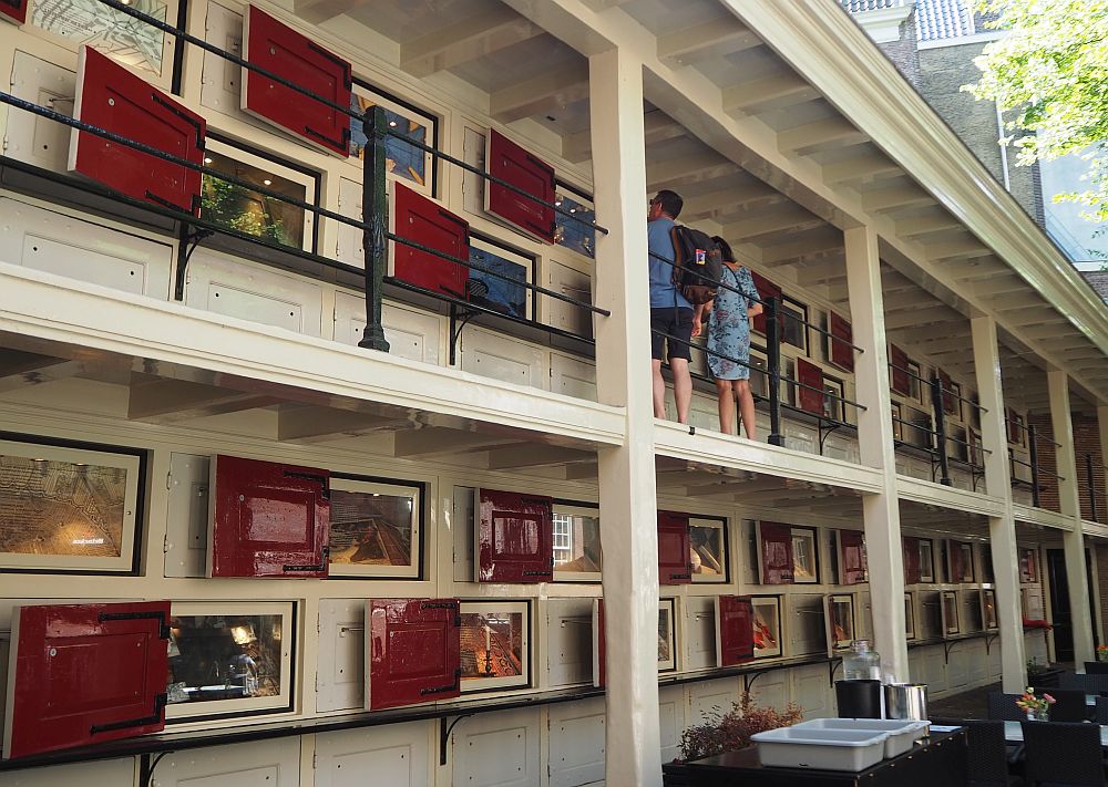 The lockers are arranged along a wall, in two rows on the ground floor and then two more rows along a gallery upstairs. Each has a red door, now open to show the exhibits in each one.