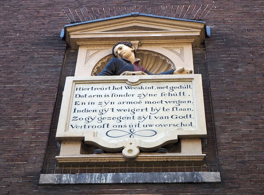 This image is set high on the wall to the side of the entrance to the Amsterdam Historical Museum. Above the verse is the torso of a boy, looking sadly to the side.