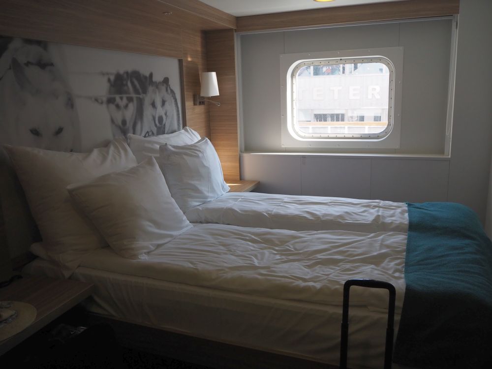 double bed with the head at the left, a large black and white photo of sled dogs on the wall at the head of the bed. Beyond the bed is a window.