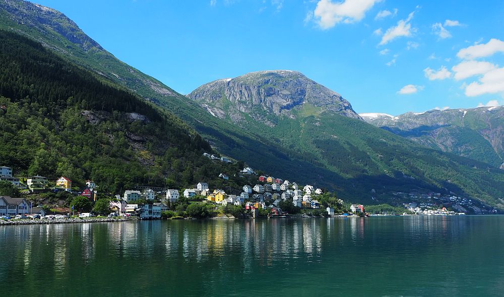 In Oddo, Norway, a cluster of colorful houses stand on the shore of a lake, backed by mountains.