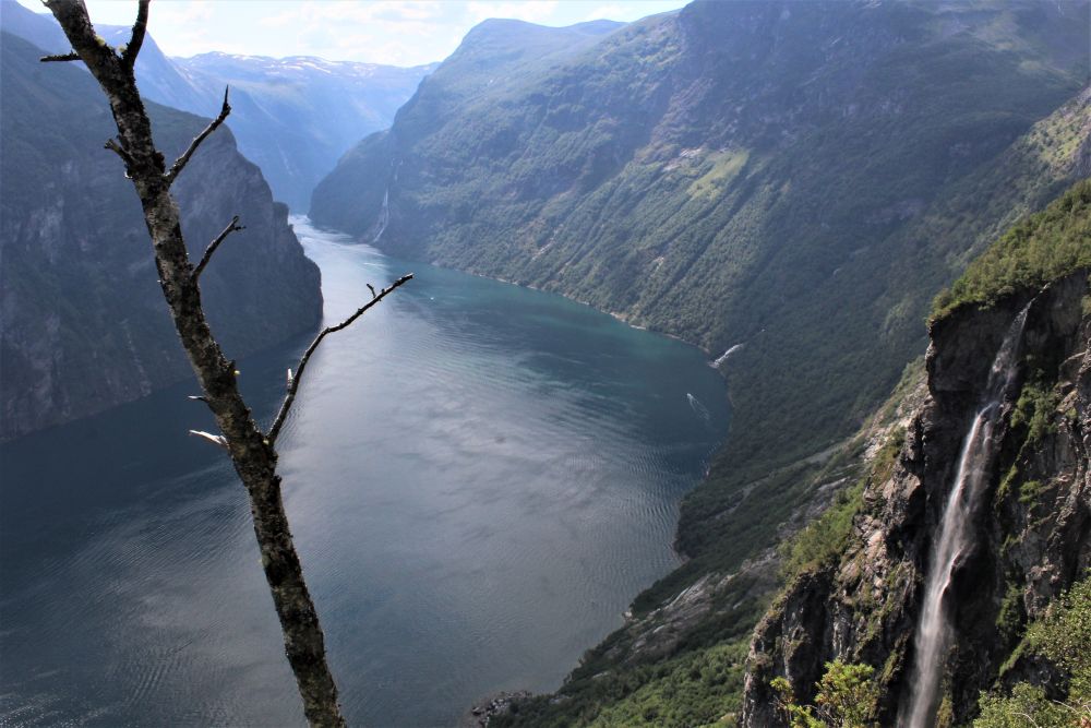 The narrow strip of water is lined with steep sided mountains, and a waterfall is visible in the foreground.