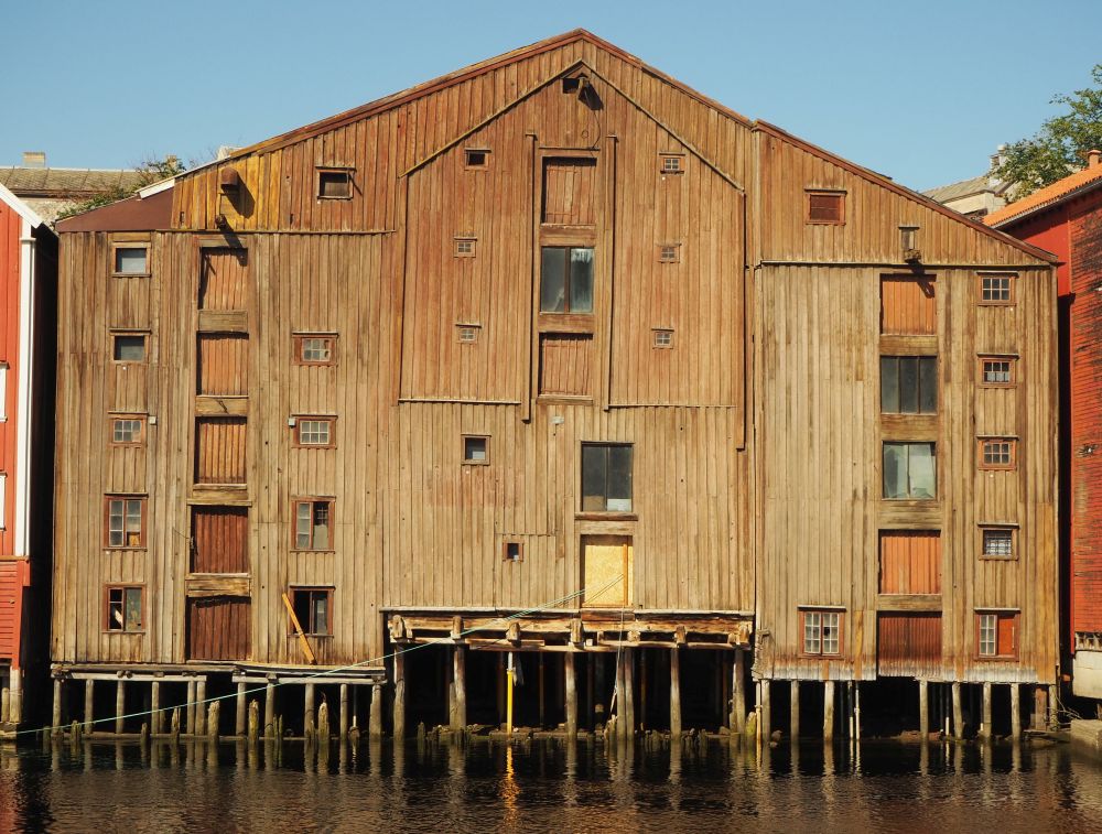 This warehouse is brown wood and looks quite massive from this vantage: 6 or 7 floors, and resting on pillars. Beams stick out above the bigger windows/doors that must have been used in the past to lift cargo from boats into the warehouse.