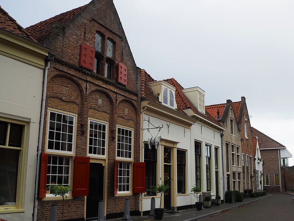 A row of little houses: some red brick and some painted white. One has a shop sign sticking out from it that is a carving of a sheep.