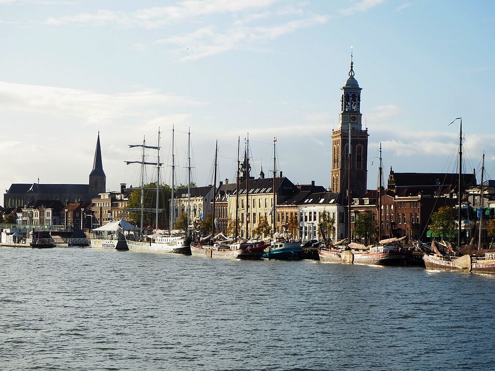 Along the waterfront are some largish rowhouses, two or three stories tall. Moored alongside them are tall-masted ships, some of which look quite old. On the left is a church and toward the right, behind the houses, is a tall church tower. Our Boat Bike Tours Hansa Highlights trip left from here.