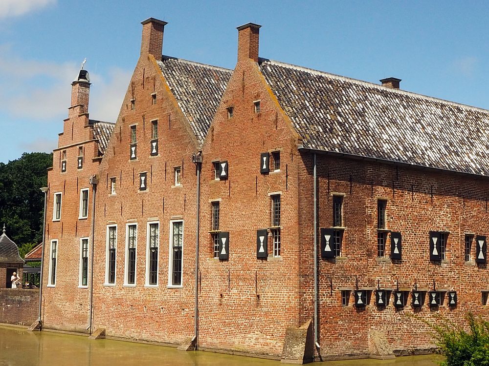 From this view, Menkemaborg looks like 3 row houses together, with three gables on the back of the house. The left-hand one is a tall step gable, while the other two are much simpler pointed gables. All three have what looks like a small chimney at the peak. The windows also vary in size. On the left two parts of the house the ground floor windows are tall and the upper floors are smaller. On the right-hand part (presumably the oldest), all of the windows are small. 