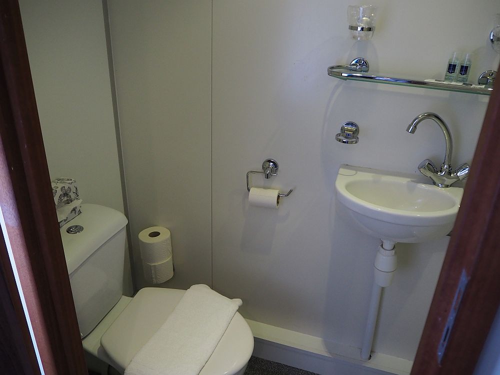 The toilet in our Boat Bike tours cabin is visible on the left and the sink is on the wall opposite the camera.