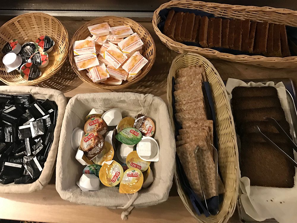 Breakfast on Boat Bike Tours: Baskets each hold a different item: margarine, butter, jam and peanut butter, each in an individual single serving package. Also 3 more baskets holding ontbijktkoek (a sweet spice loaf), roggebrood (a dense thin-sliced pumpernickel) and whole wheat crackers.