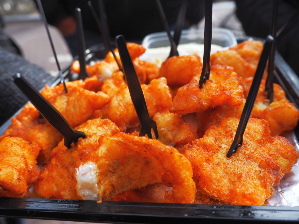 chunks of fish with a fried battered topping. Some have small brown plastic forks sticking up out of them.