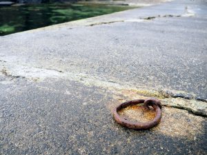 a close-up of a cracked concrete surface with a round, rusty circle of iron attached to it.