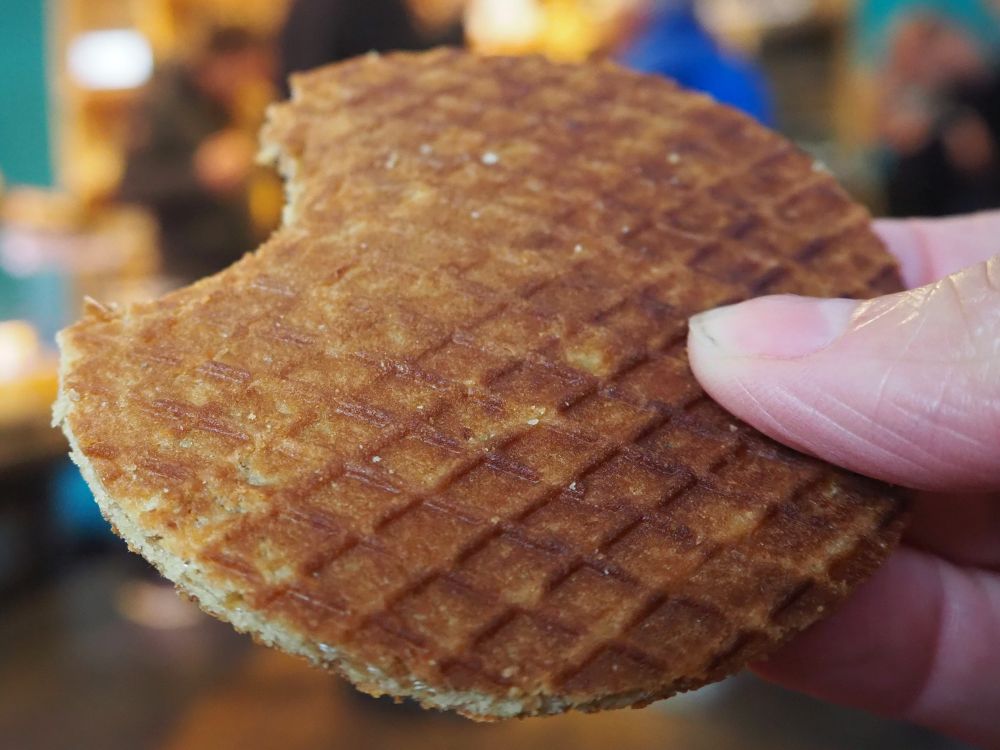 close-up of a round stroopwafel with one bite already taken out of it.