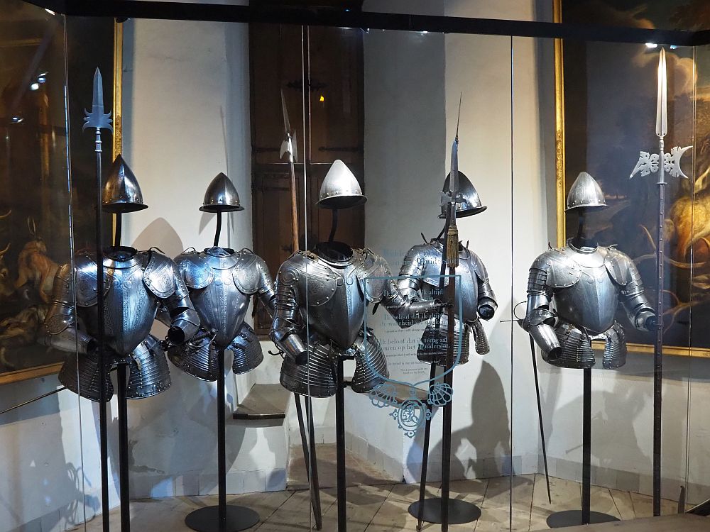 Five suits of armor stand on simple poles. Each has just the top half of a coat of armor.