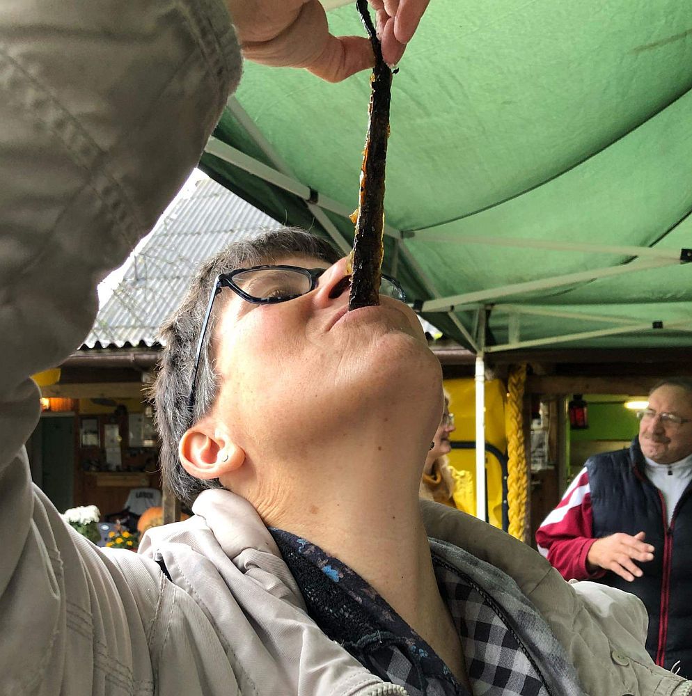 Me, hold my head back, holding the fish up by one end and the other end in my mouth.