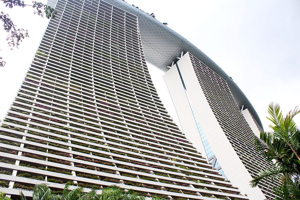 a view of Marina Bay Sands hotel, one of the Singapore film locations, as seen from the bottom of one of the towers. It curves gradually up to the surfboard shaped top.