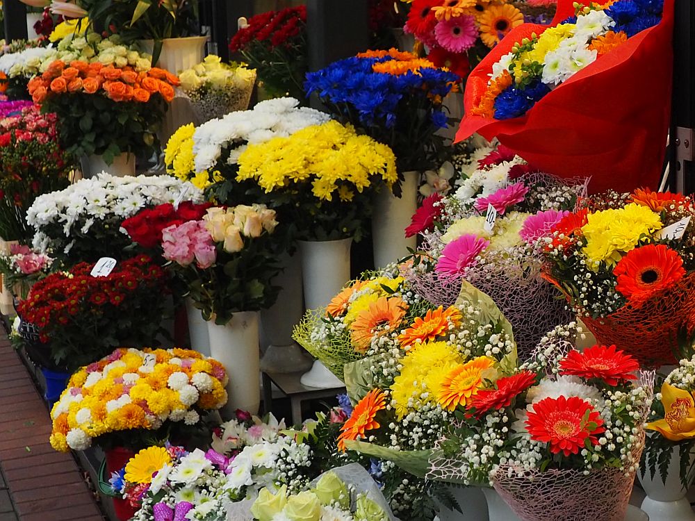 A close-up of a display of bouquets of flowers in very bright colors: pinks, reds, yellows, oranges and white primarily. 