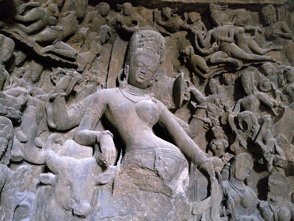 The central figure is a woman, standing with her hip jutting out to the right. From the hips down is destroyed. Around her are many smaller figures in different poses, some quite damaged but some intact and detailed.