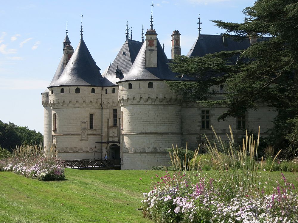 The castle has a rounded tower on each side of the entrance, and each tower is topped with a pointed grey turret. 