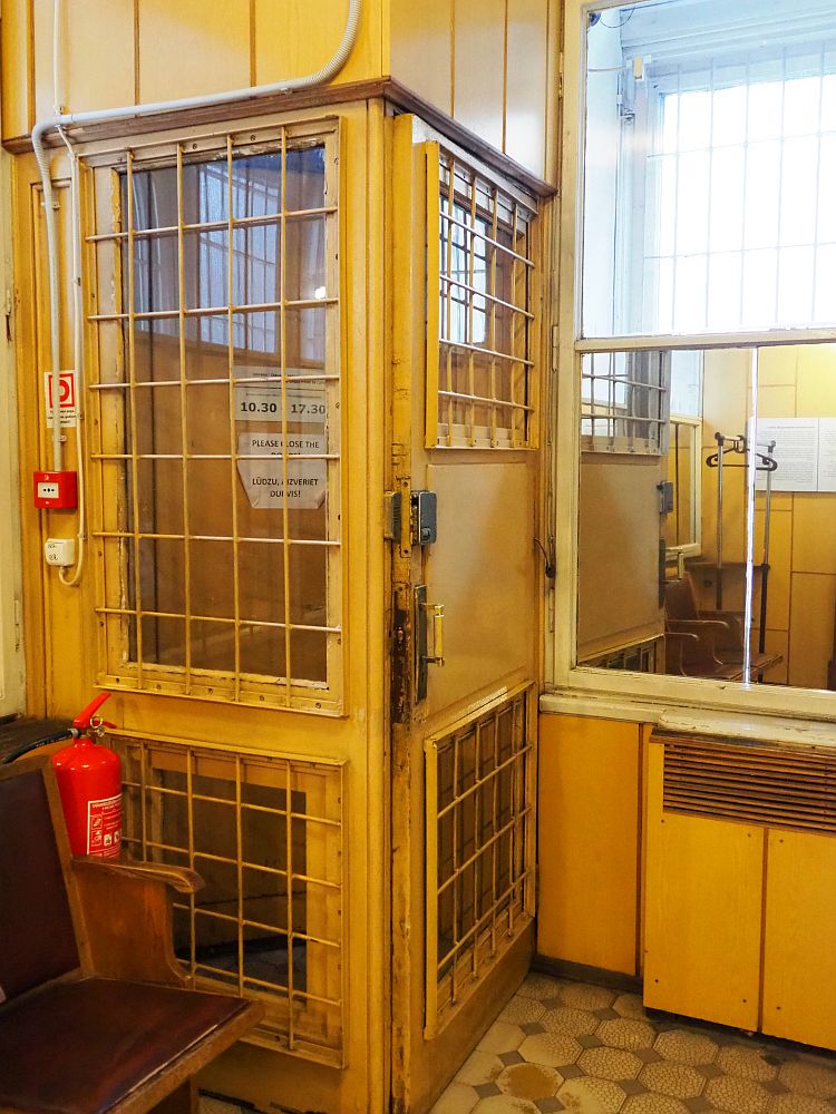 The caged door of the museum. It's about the size and shape of a telephone booth, but barred on the two near sides, with the doors to the street on the other side. It's a sickly yellow color.
