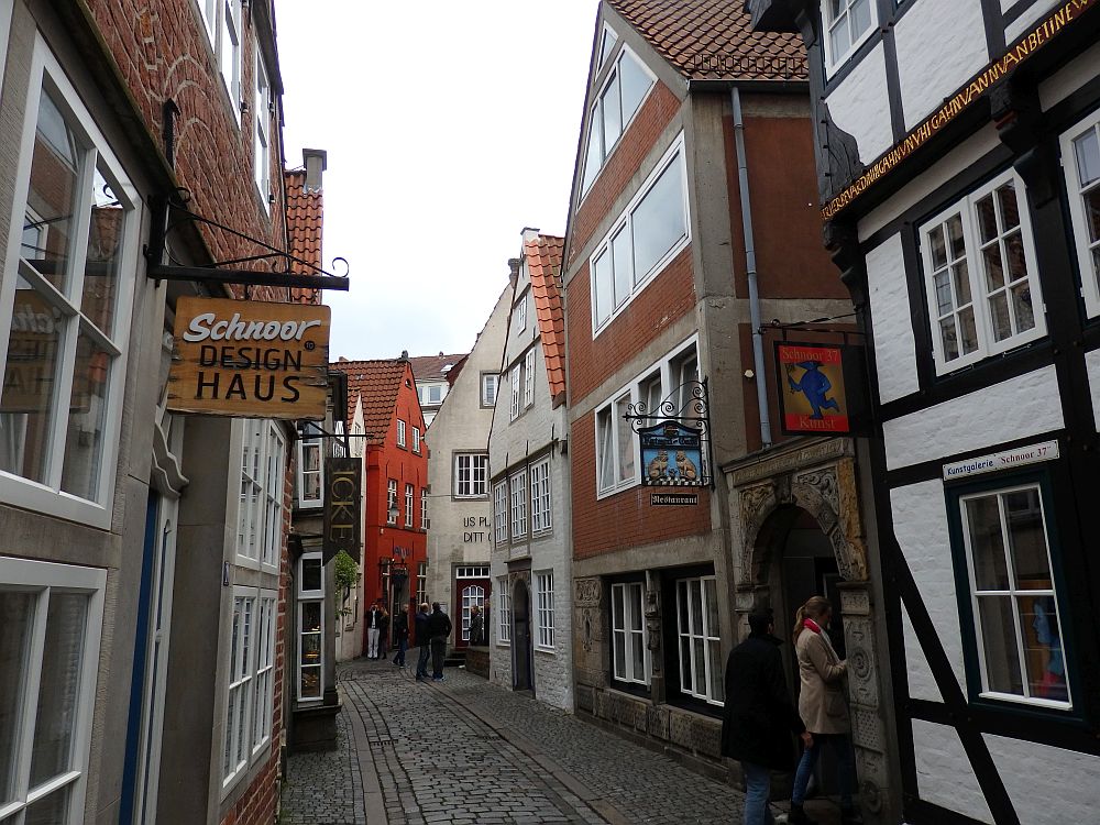 A narrow cobbled street. the houses vary in age. Some have exposed timbers and many lean a bit one way or another.