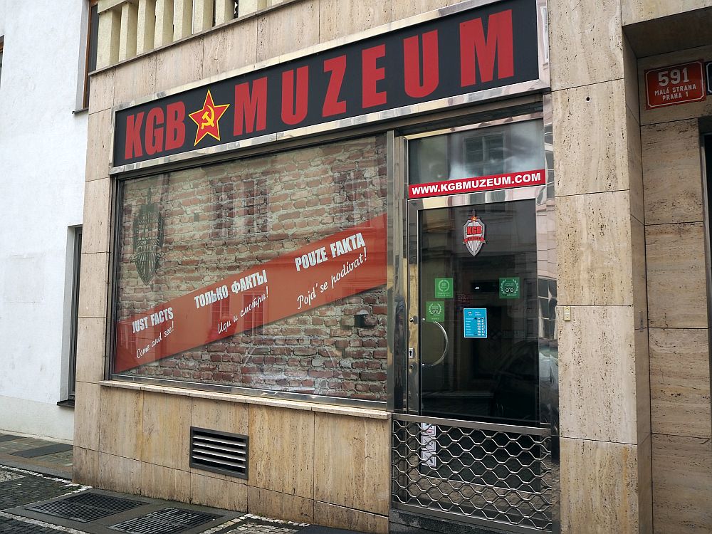 The store front reads "KGB Muzeum" with a red star with a hammer and sickle inside it. The store window appears to be bricked up.