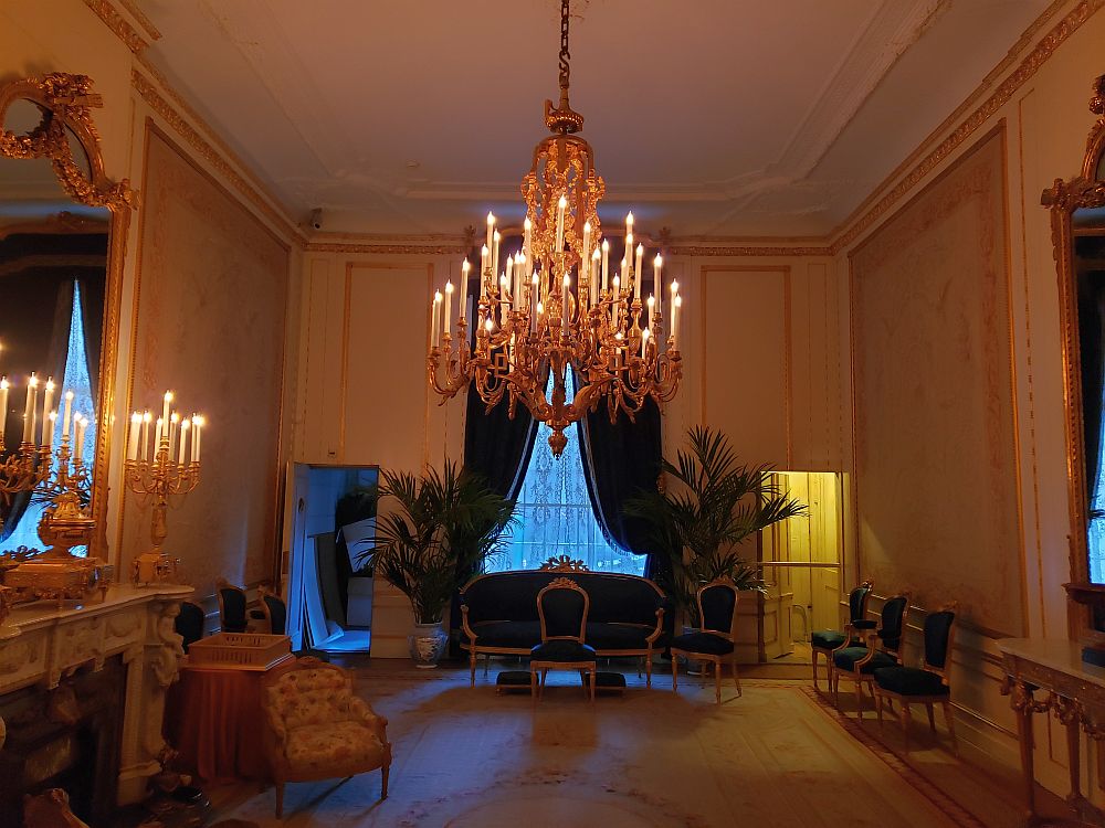 The Willet-Holthuysen Museum's ballroom is a large open room, with the furniture -- mostly just chairs and one sofa, along the walls. A massive chandelier hangs from the center, low enough for a tallish man to bump his head. Behind that is a large window with dark drapes pulled to each side. On the left is a highly-decorated fireplace with a gold-framed mirror above it.