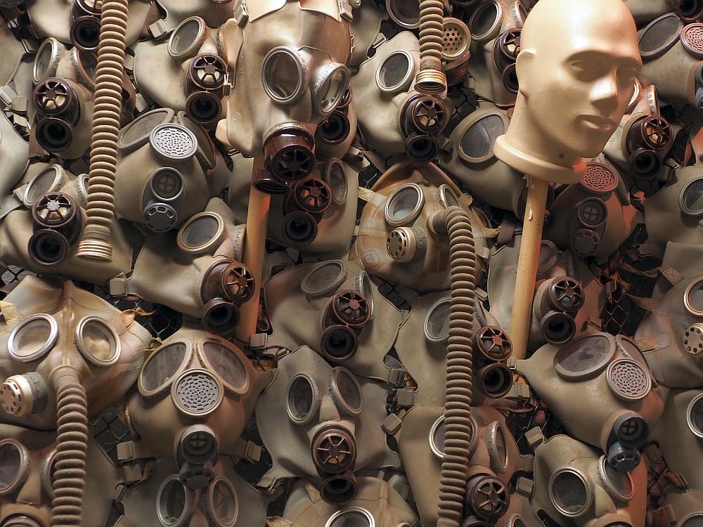 The gas masks are mounted on the wall so that none of the wall is visible: it's just a hodgepodge of gas masks and hoses and one mannequin head.