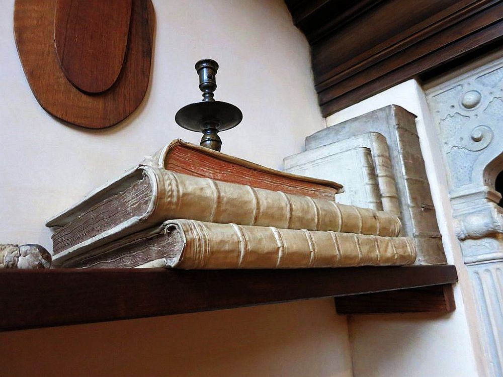 A mantel with several old leather-bound books and a candle holder.