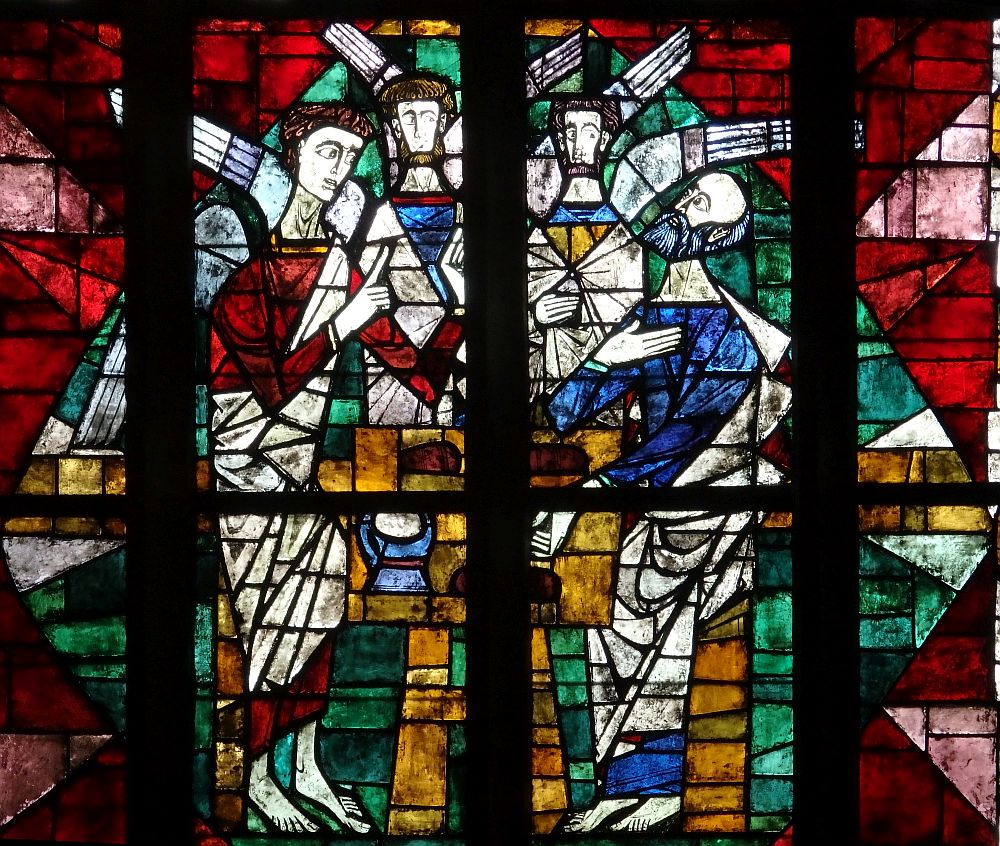 A stained-glass window depicts three angels with wings speaking to a man.